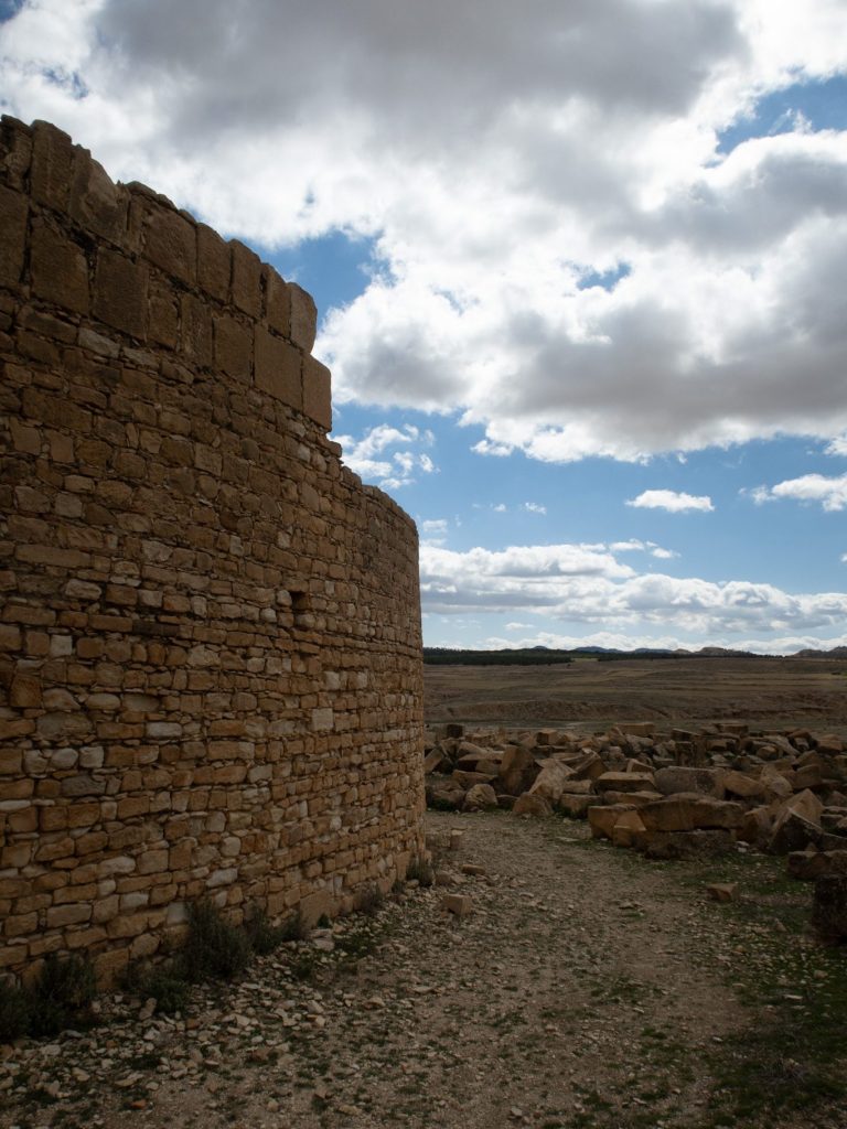 Side view of a large, curved stone wall, part of the Byzantine fortress at Ammaedara in Haïdra, Tunisia, with rocky terrain